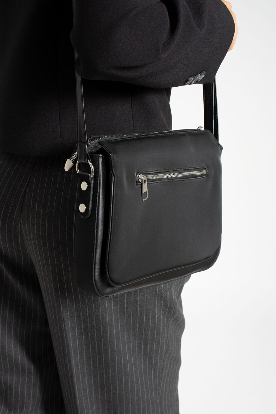 Back view of a Sanmorris 3-compartment crossbody bag in black faux leather, showcasing a secure metal zippered pocket and adjustable shoulder strap, ideal for daily use or business settings.